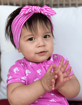 Baby girl is wearing a comfortable baby headband for little girls from By Bella Boutique.